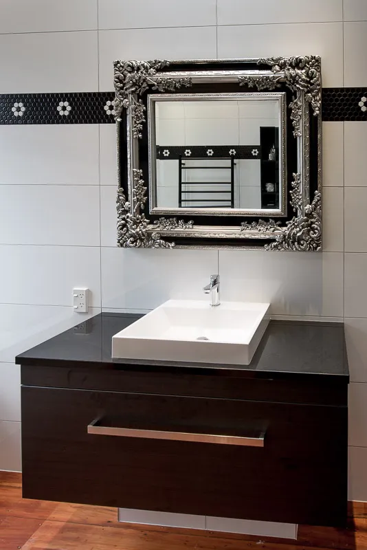 Luxury bathroom vanity with black cabinetry and decorative framed mirror