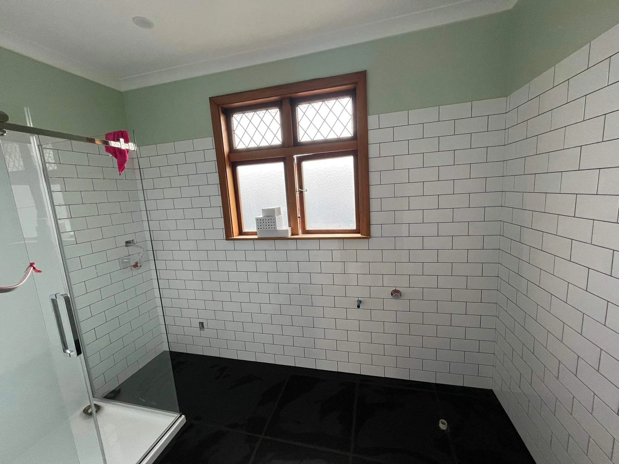 Bathroom renovation in progress showing white subway tile installation with mint green walls