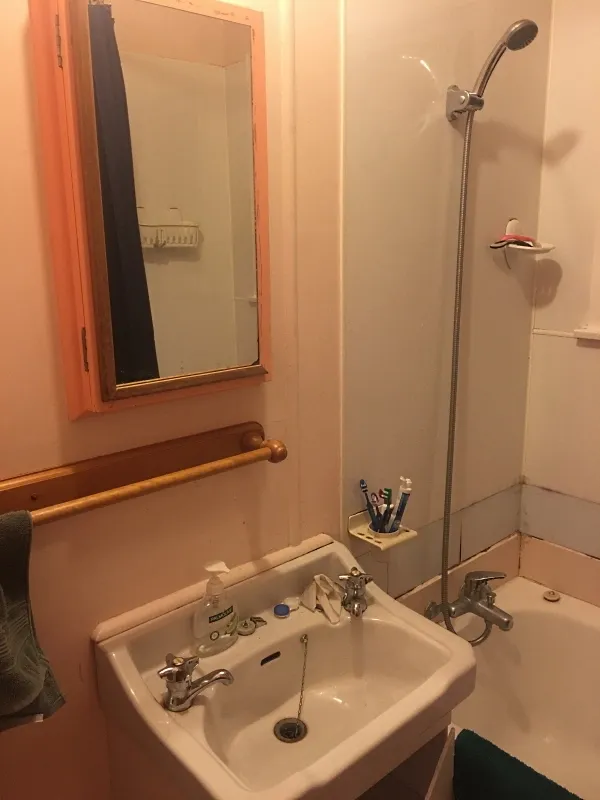 Before renovation: dated bathroom with salmon walls, basic fixtures and pedestal sink