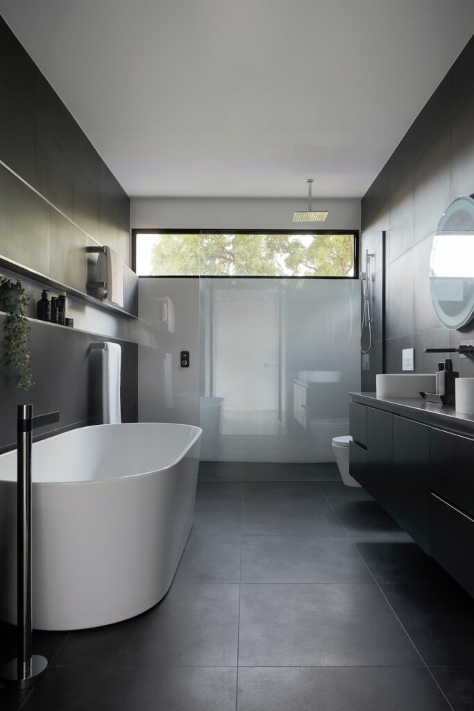 Charcoal tile floor and walls with seamless glass shower